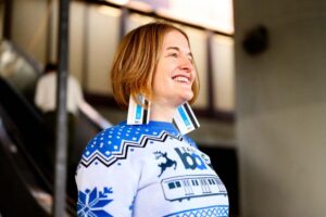 Woman sports BART holiday sweater and fare card earrings.