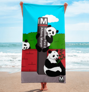 Washington Metro beach towel featuring illustration of pandas frolicking around Woodley Park-Zoo/Adams Morgan Metro sign.