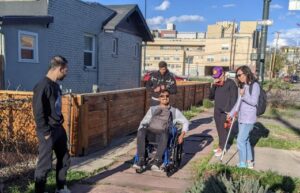 Students use wheelchairs and white canes to experience broken sidewalks and other transportation challenges.
