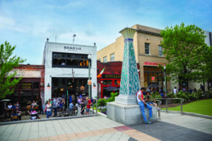 People congregate in Decatur Square with patrons seated at restaurant in background.