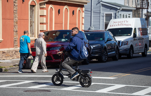 Man on e-bike crosses street.